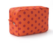 An orange zippered cosmetic pouch with a dark red polka dot pattern, shown on a clean white background.