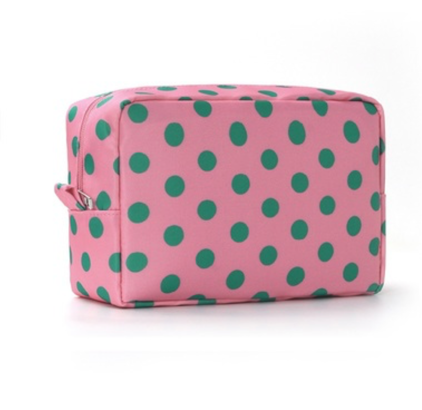 A pink cosmetic pouch with a green polka dot pattern, shown on a clean white background.