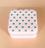 A square zippered storage box with a white textured fabric cover decorated with green polka dots, set against a solid beige background.