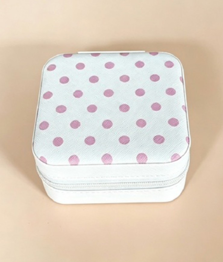 A square zippered storage case with a white textured surface covered in pink polka dots, set against a solid beige background.
