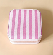 A square zippered pouch with vertical pink and white stripes, shown from a top-down view on a solid beige background.