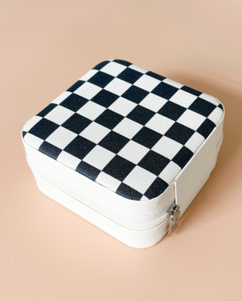 A square zippered case with a black and white checkerboard pattern on the top, shown on a solid peach background.
