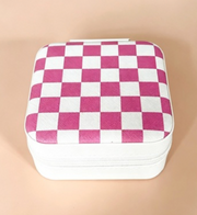 A square zippered case with a pink and white checkerboard pattern on the lid, set against a solid beige background.