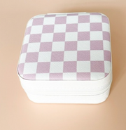 A square zippered storage box with a lavender and white checkerboard pattern on the lid, set against a solid peach background.