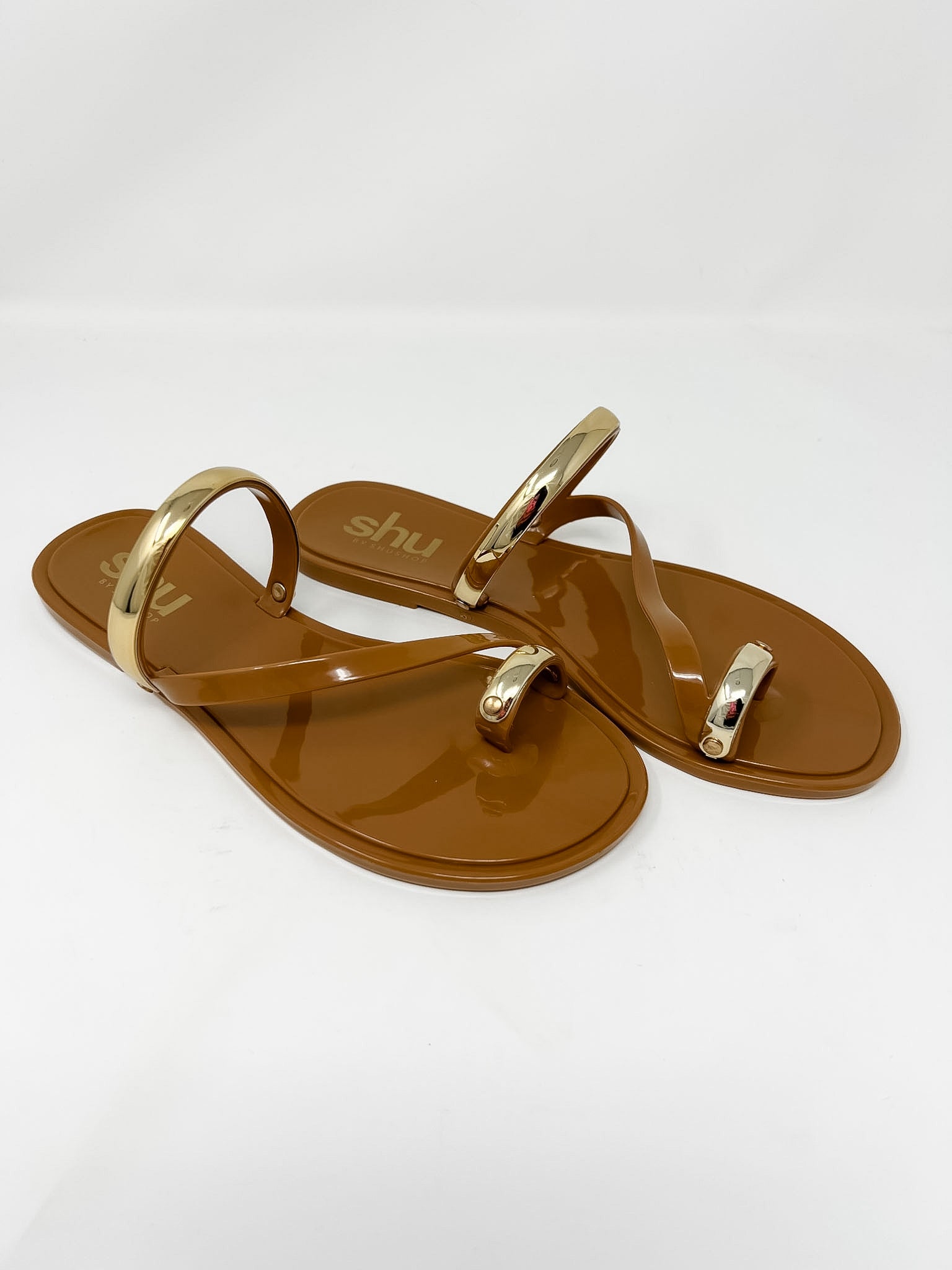 Brown sandals with gold straps on a white background