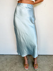 Person wearing a light blue satin skirt against a white background