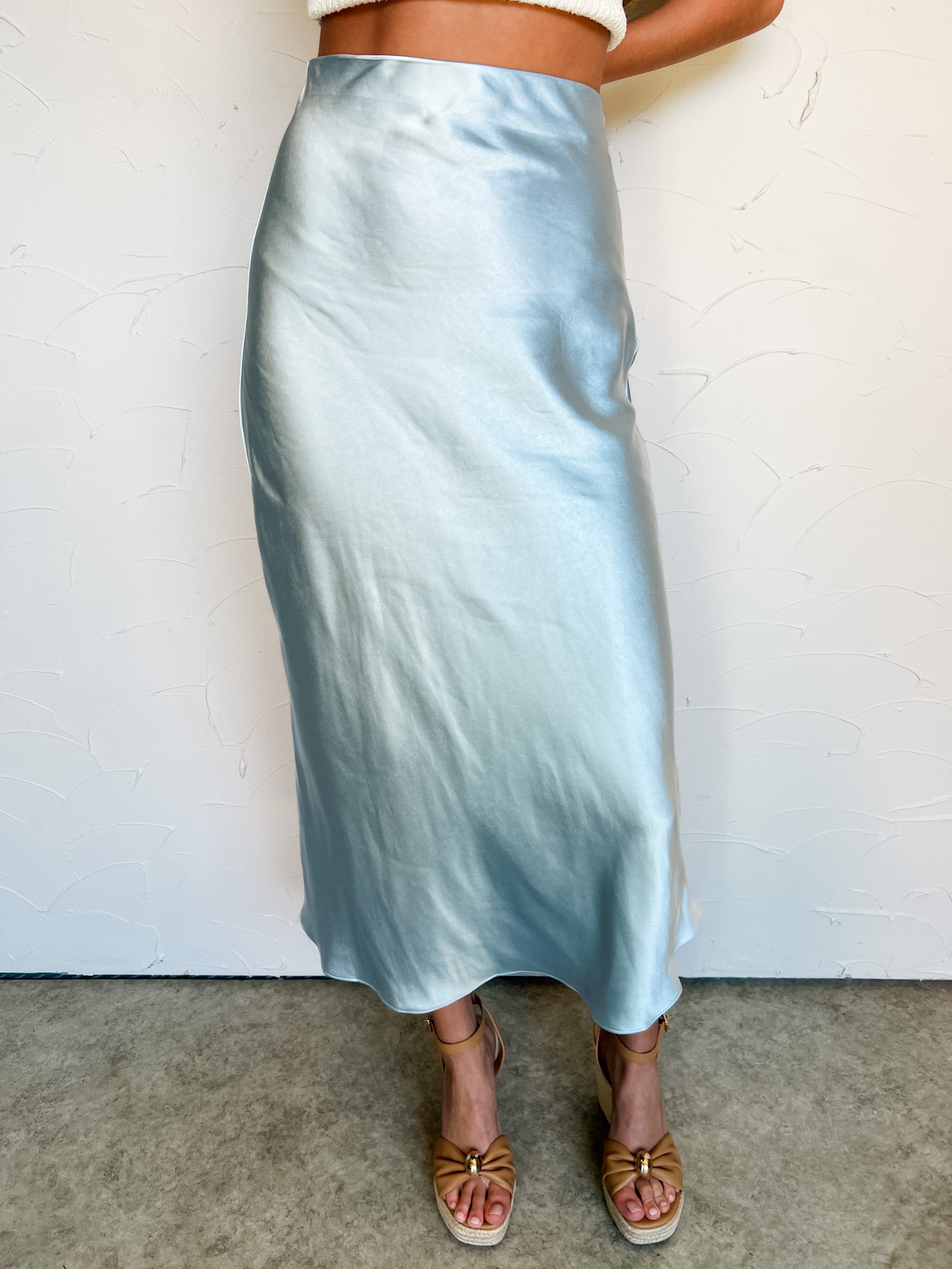 Person wearing a light blue satin skirt against a white background