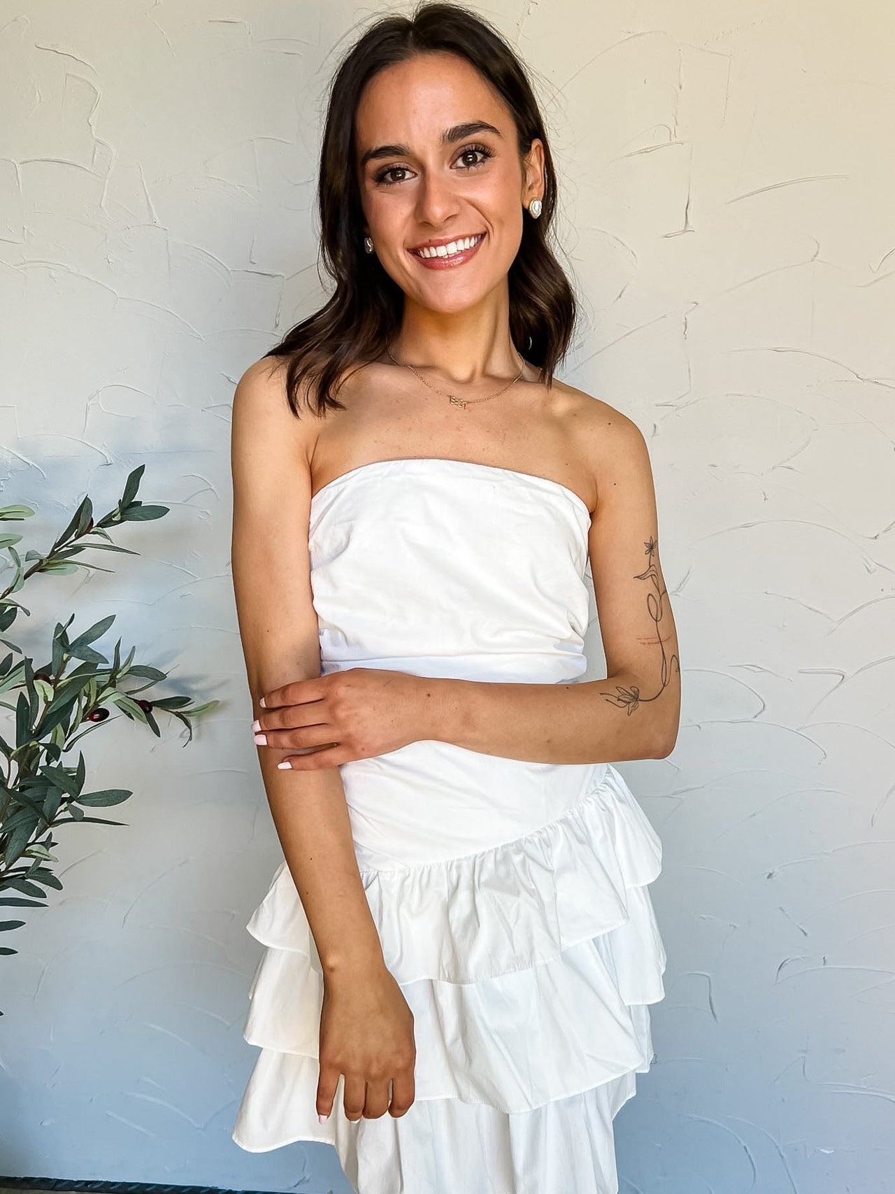Woman wearing a white strapless dress with ruffles against a light background