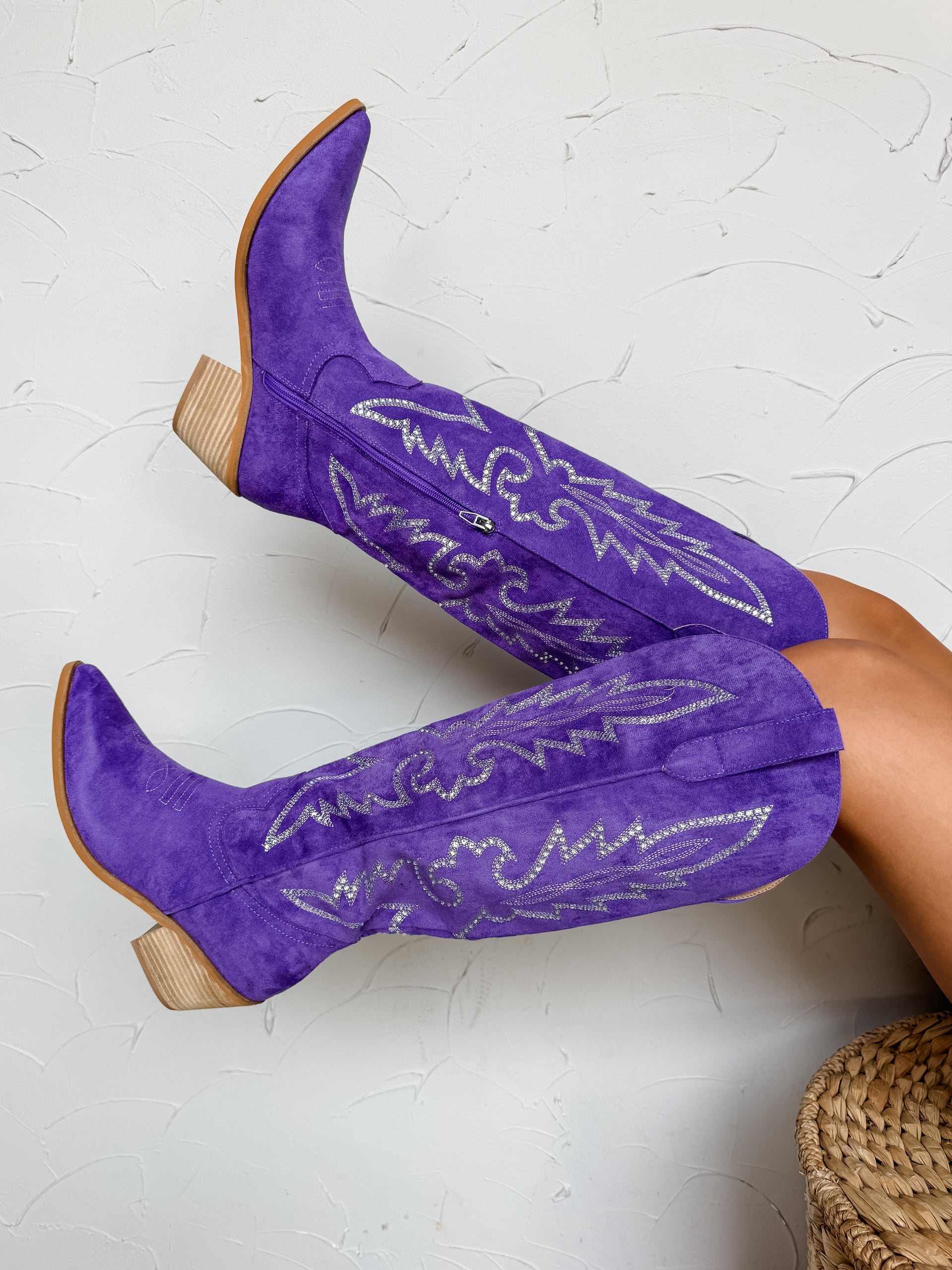 Purple cowboy boots with white text on a textured white background