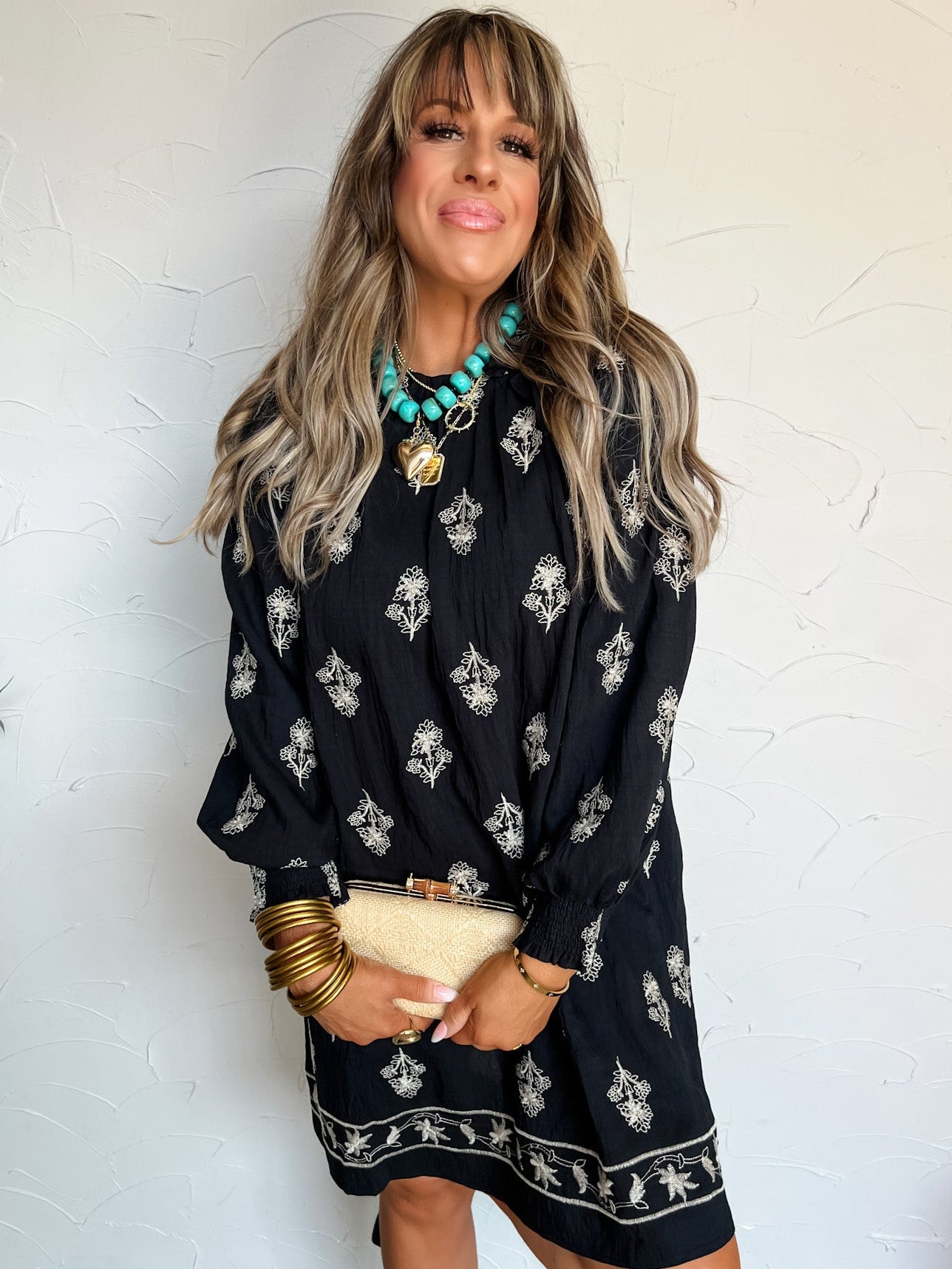 Woman wearing a black patterned dress with a white brick wall background