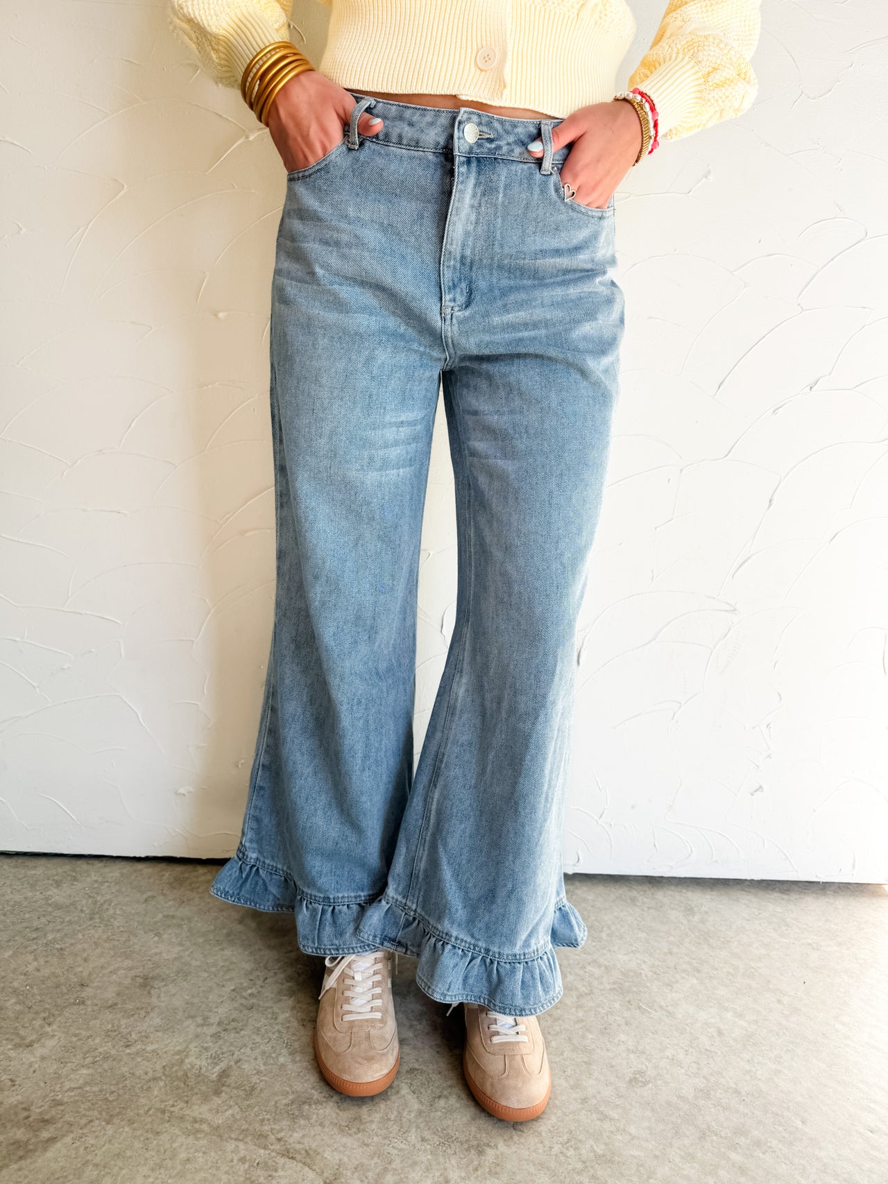 Person wearing light blue flared ruffle jeans with a plain background