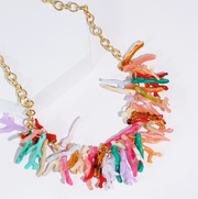Colorful coral-like necklace with a gold chain on a white background