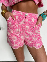 Person wearing pink floral shorts on a white background