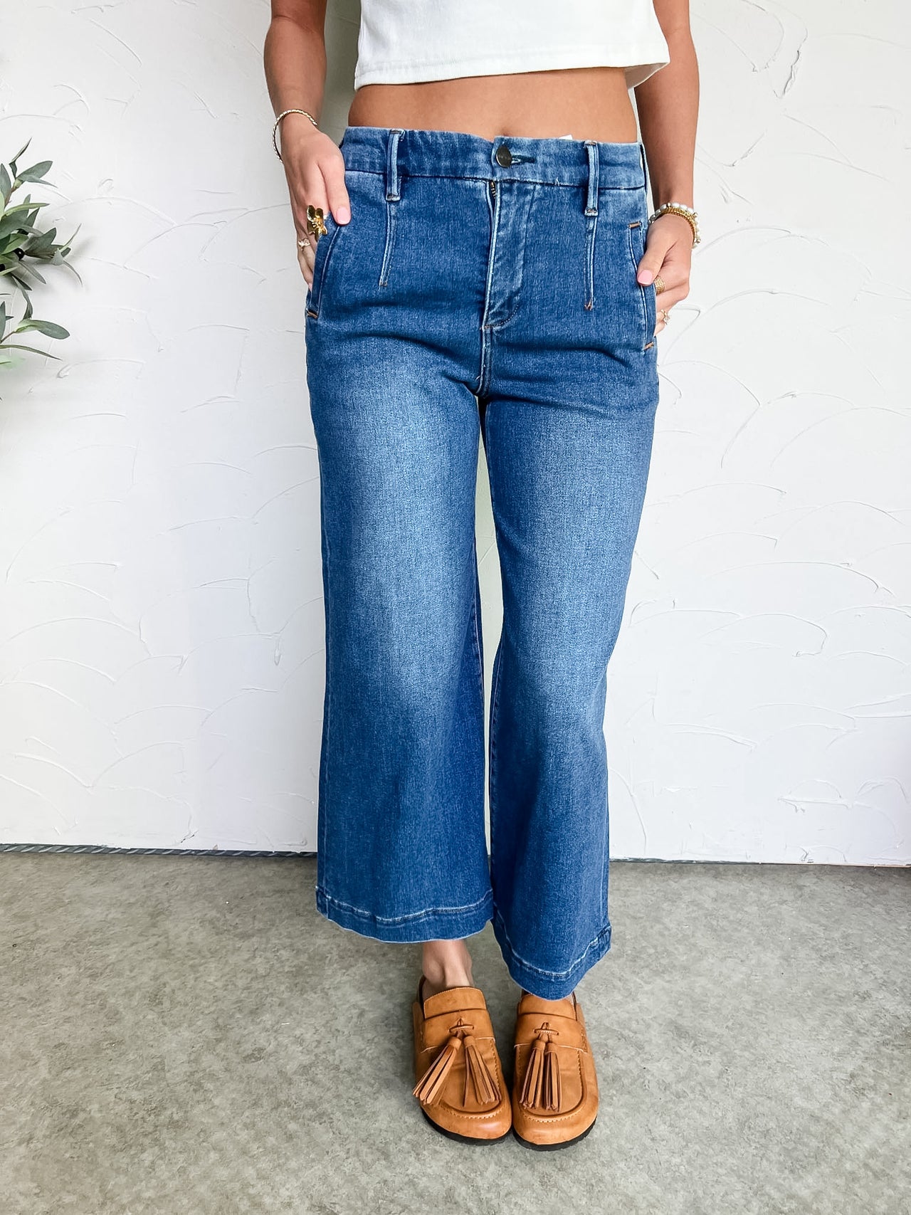 Person wearing blue jeans and brown loafers on a plain background