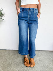 Person wearing blue jeans and brown loafers on a plain background