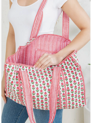 Person wearing a red and white striped apron with floral patterns on a plain background