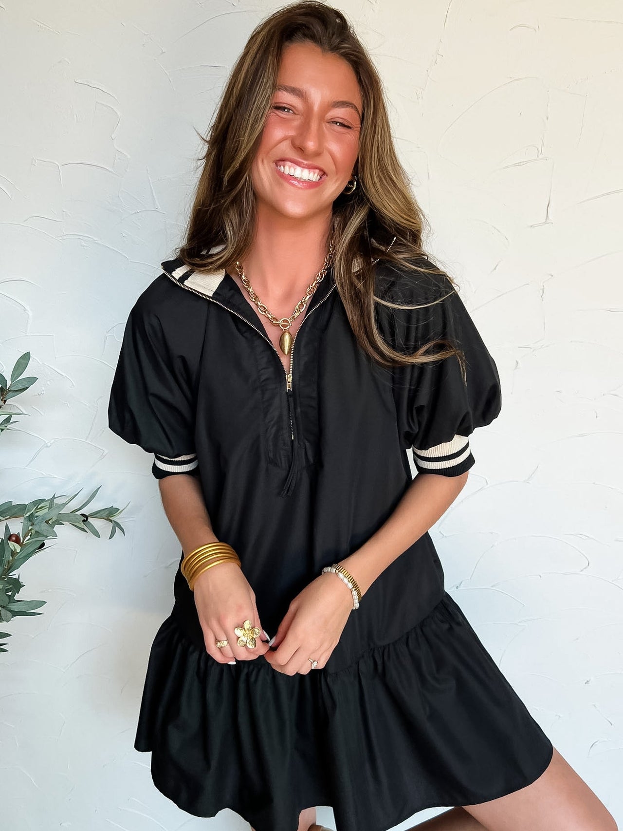 Woman wearing a black dress with white detail against a white wall