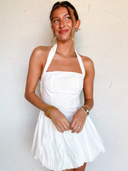 Woman wearing a white halter dress against a light background