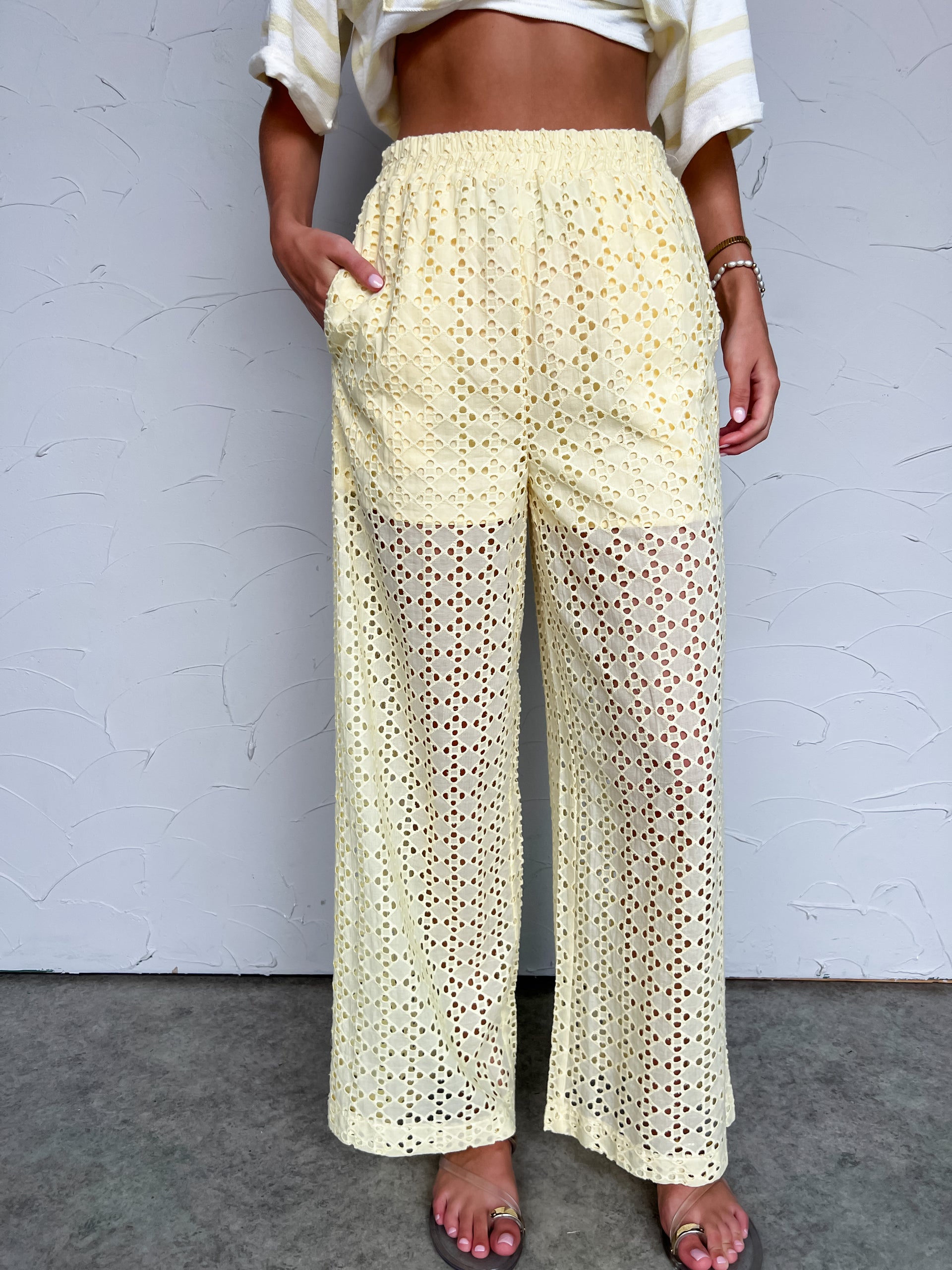 Person wearing light yellow lace pants against a plain background