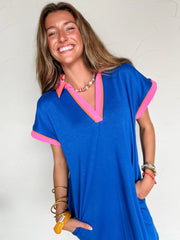 Woman wearing a blue dress with pink and orange accents against a white background