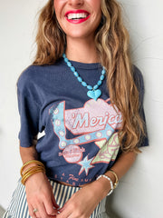 Woman wearing a graphic t-shirt with '''merica" design against a white wall