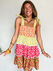 Woman wearing a colorful floral dress against a white wall