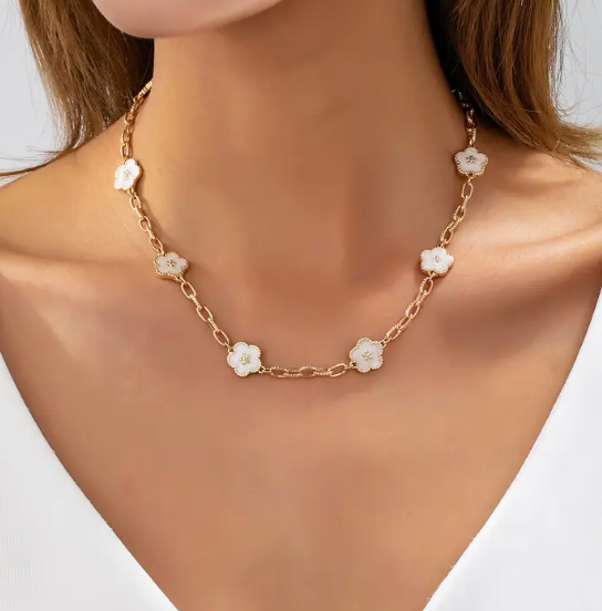 Gold necklace with floral pendants on a model against a neutral background