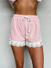 Pink shorts with lace trim worn by a person on a light gray background