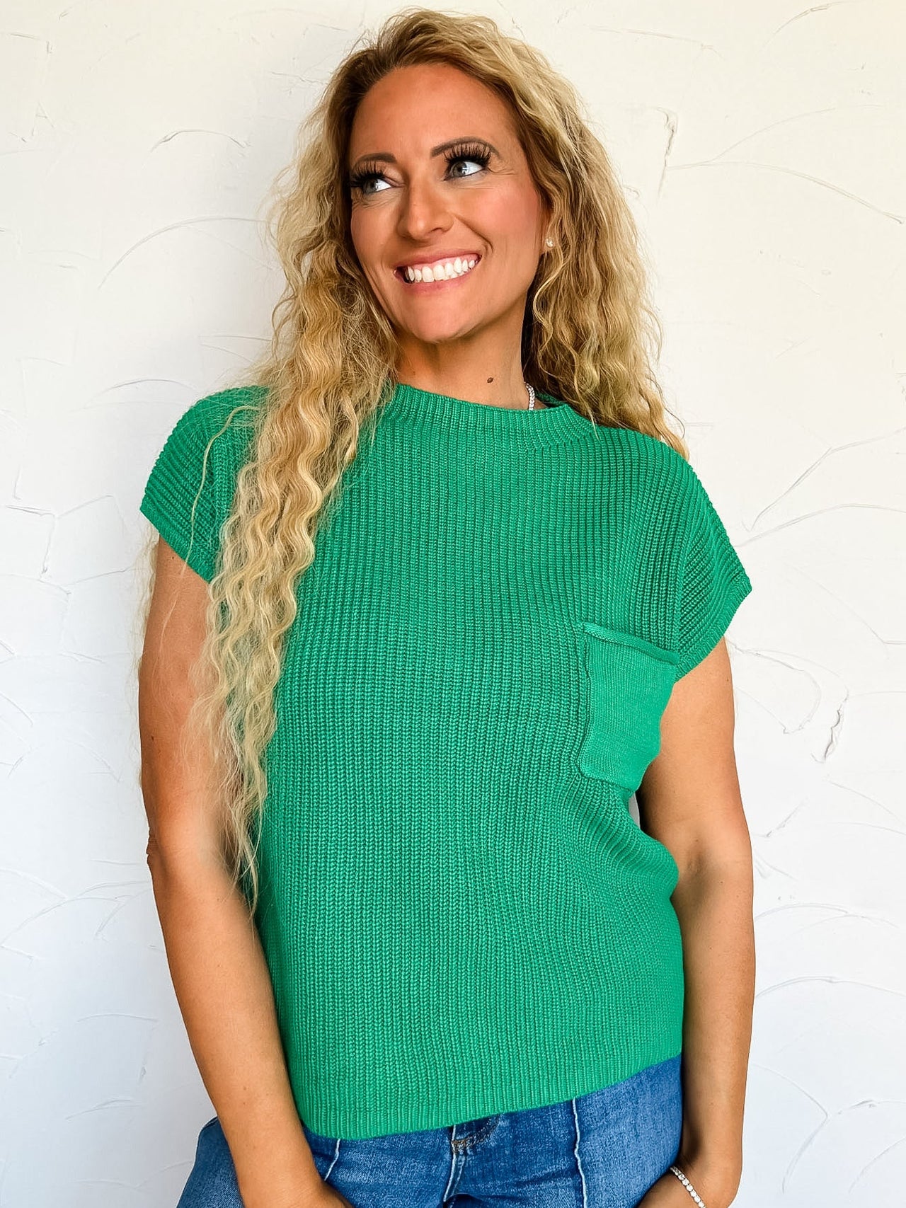 Woman wearing a green short sleeve sweater against a white background