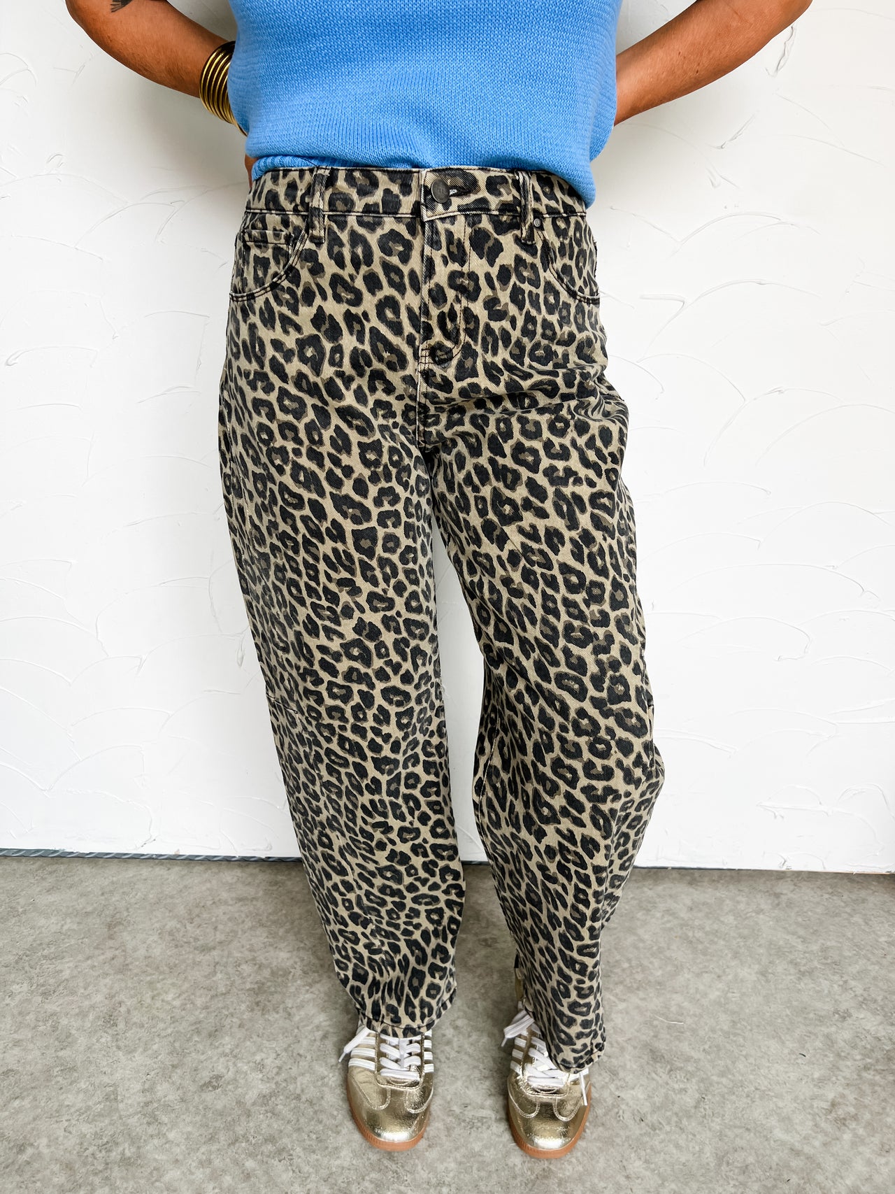 Person wearing cheetah print pants and a blue top against a white background