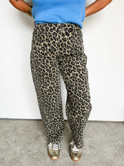 Person wearing cheetah print pants and a blue top against a white background