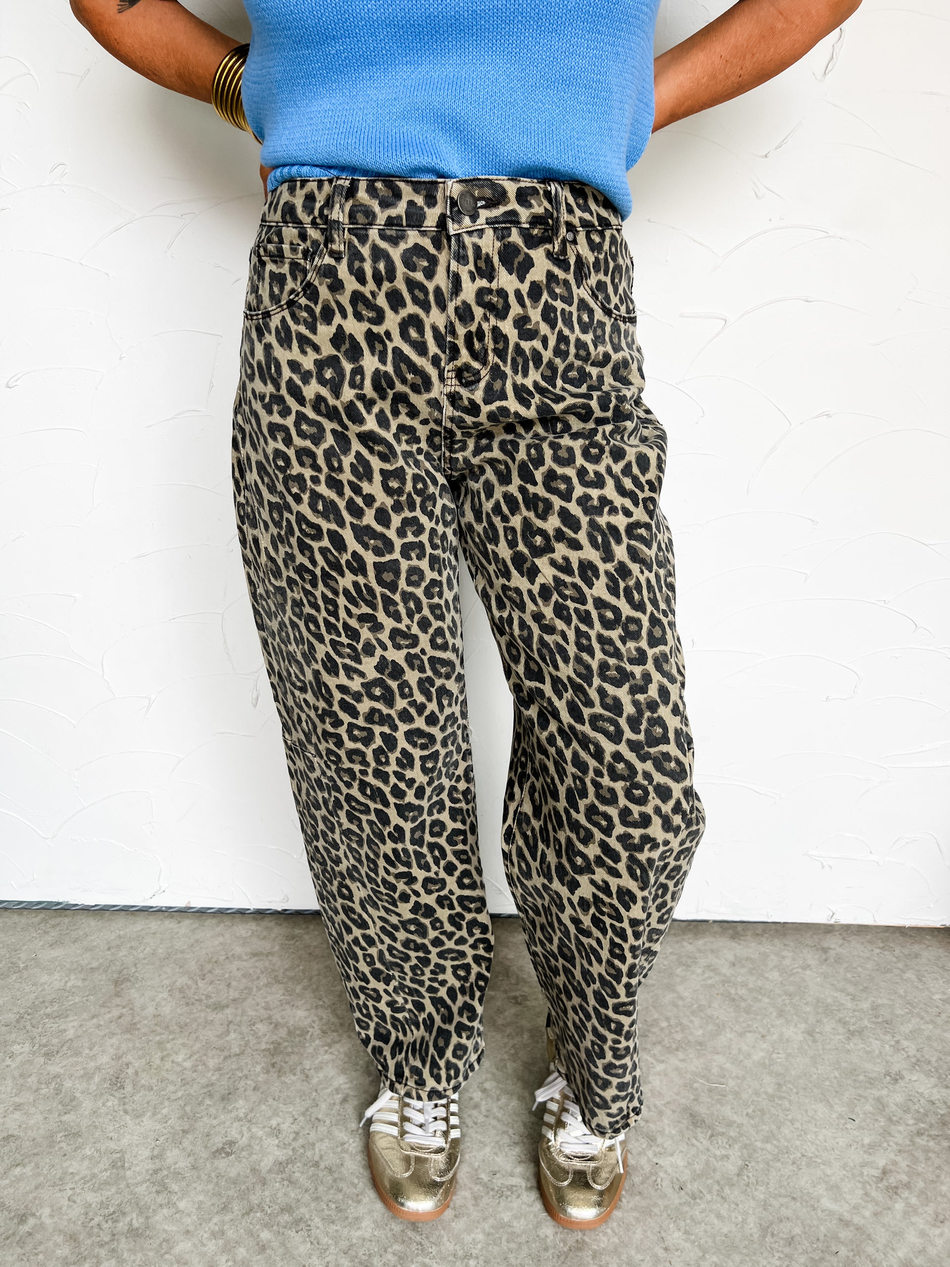 Person wearing cheetah print pants and a blue top against a white background