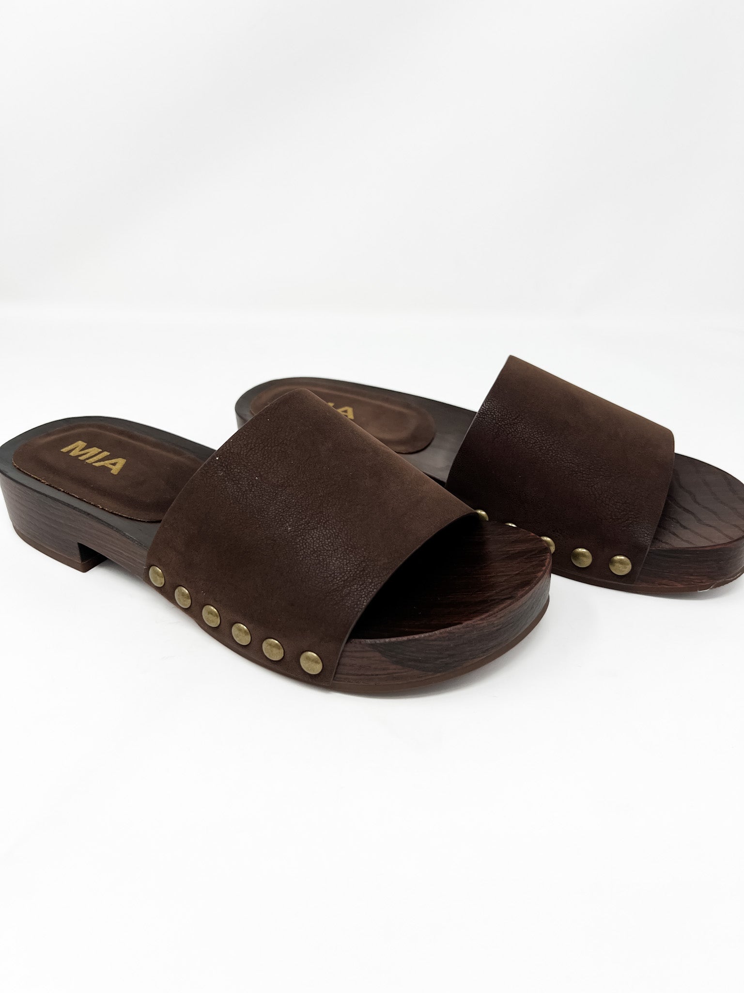 Pair of brown sandals with gold studs on a white background