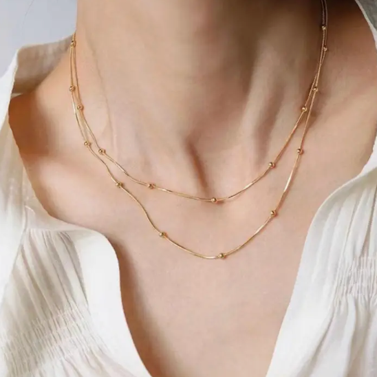 Gold necklace on a person wearing a white top