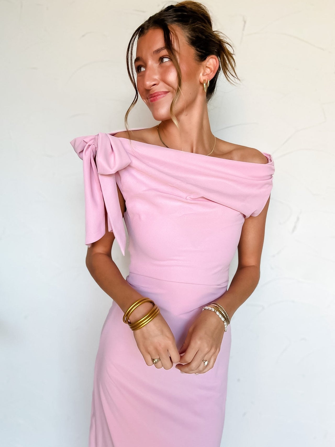 Woman wearing a pink off-shoulder dress with a white background