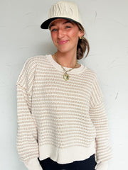 Woman wearing a beige and brown mix sweater and cap with 'Texas' text against a white background