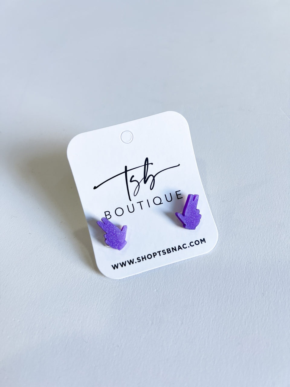 a pair of purple earrings on a white label