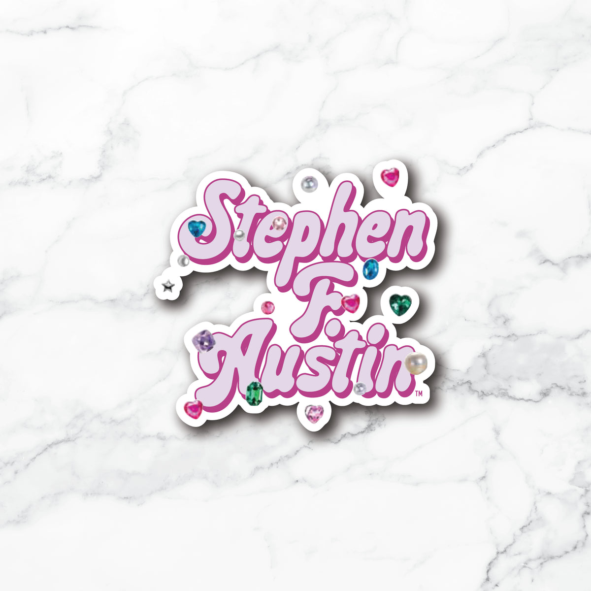 A die-cut vinyl sticker with the text 'Stephen F. Austin' in pink cursive lettering, embellished with small colorful heart gems and rhinestones, shown on a white marble background.
