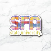 A die-cut sticker featuring the letters 'SFA' filled with a colorful patchwork pattern and the words 'state university' below in yellow, shown on a white marble background.